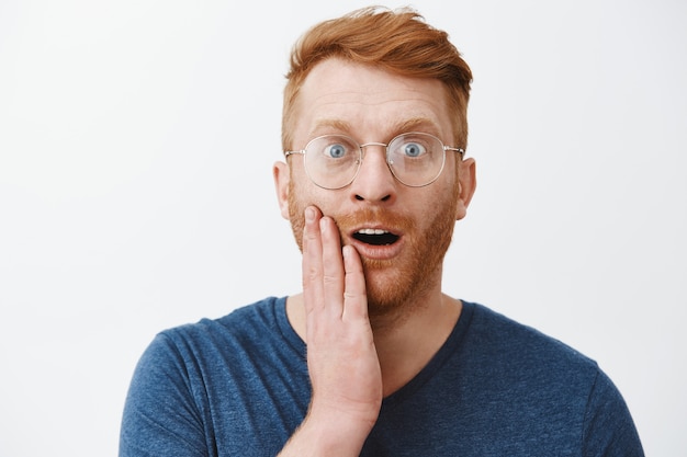 Close-up of surprised redhead adult man in glasses react to something amazing