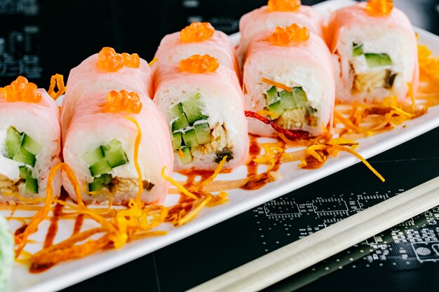 Close up of sushi rolls with cucumber and fish topped with red tobiko