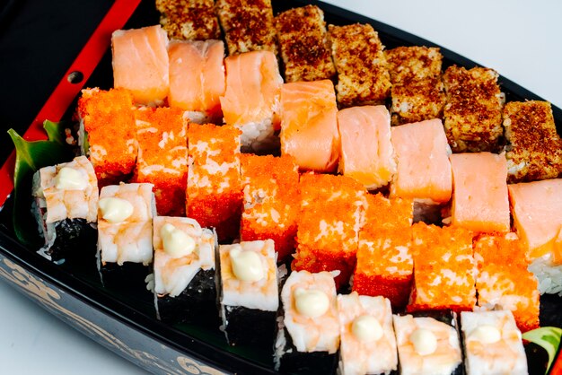 Крупный план суши с лососем, креветками, красным тобико и горячими роллами