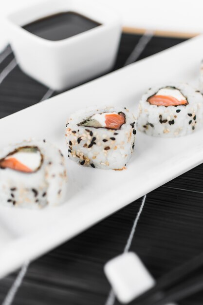 Close-up of sushi with soya sauce in bowl on place mat