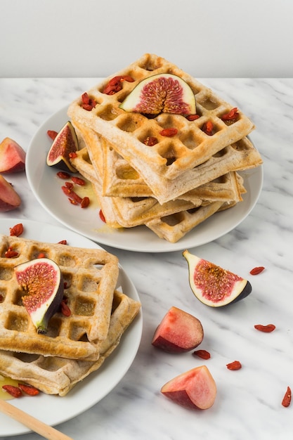 Free photo close-up of sweet belgian waffles; and fig in plate over white background