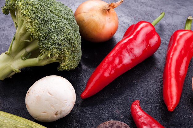 Close up of sweet red pepper, broccoli, mushrooms and onion on dark vintage wooden table