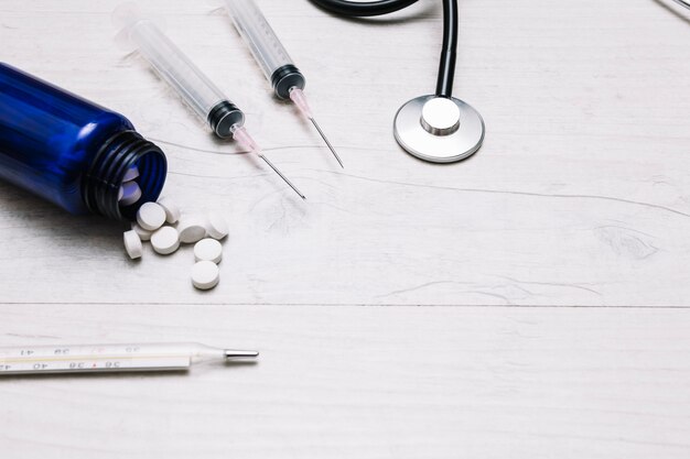 Close-up tablets and syringes near thermometer and stethoscope