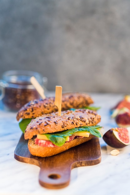 Close-up of tasty hot dogs over wooden chopping board near fig slices and almond