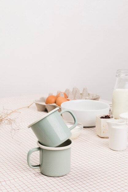 Close-up of tea mugs in front of organic ingredients over table