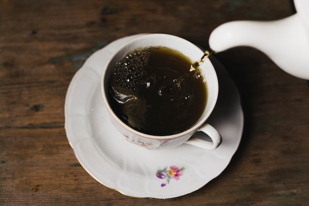 Foto gratuita tè del primo piano che versa nella tazza