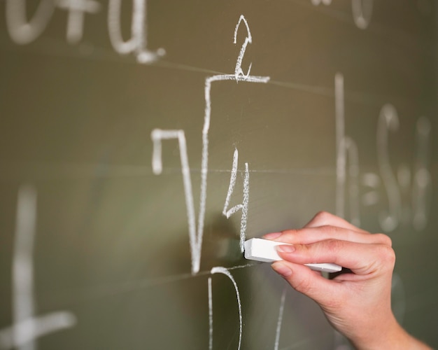 Close-up teacher writing on chalkboard