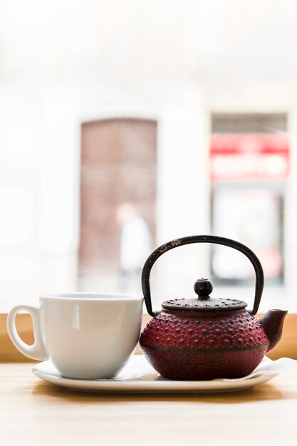 Close-up of teapot and white tea cup on wooden surface