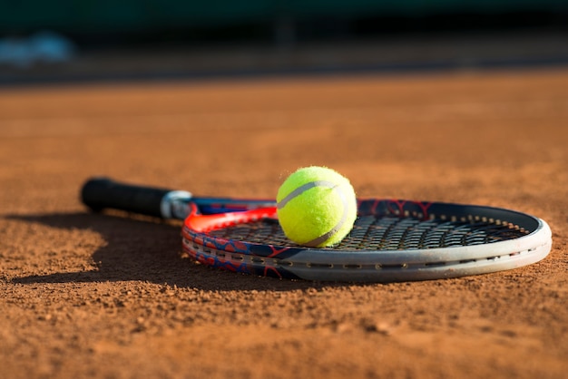 Foto gratuita pallina da tennis di primo piano su una racchetta posizionata sul pavimento