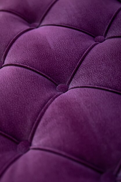 Закройте вверх по современной софе текстурированной фиолетовой бархатной ткани с затонувшими кнопками. Идея и вариант ткани для обивки дивана.