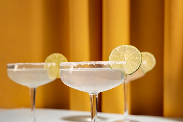 Close-up of three margarita cocktail glasses with salted rim and lime