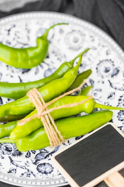 Close-up of tied green chili peppers and blank slate on plate