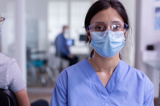 Close up of tired nurse with protection mask against coronavirus outbreak looking at camera sitting ...