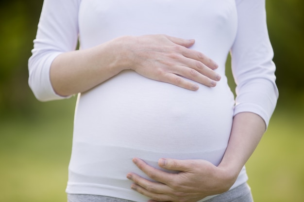 Close-up of torso of pregnant woman outdoors