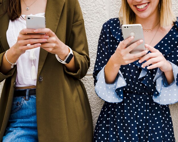 Close-up of tow friends holding mobile phone in hand