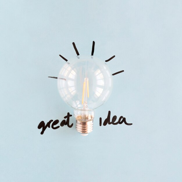 Close-up of transparent light bulb with great idea word on blue backdrop