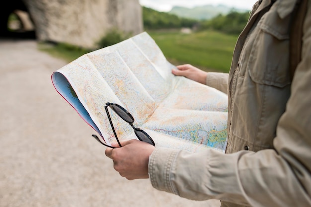 地図とサングラスを保持しているクローズアップの旅行者