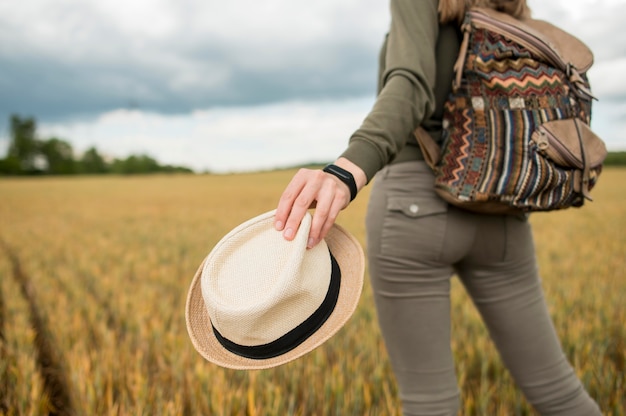 Foto gratuita viaggiatore del primo piano con il cappello della tenuta dello zaino