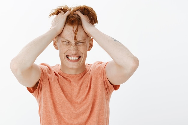 Close-up of troubled redhead man tossing hair and looking complicated, have problem