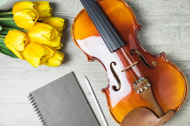 Foto gratuita primo piano di tulipani; diario; matita e violino su fondo in legno