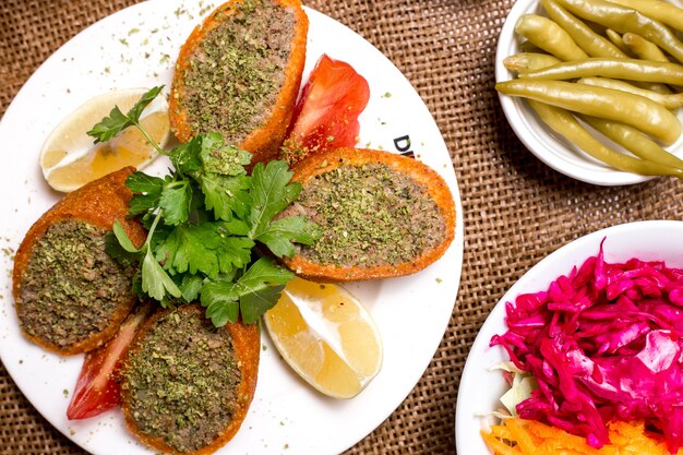 Close up of turkish stuffed meatballs ichli kofte served with lemon tomato and parsley