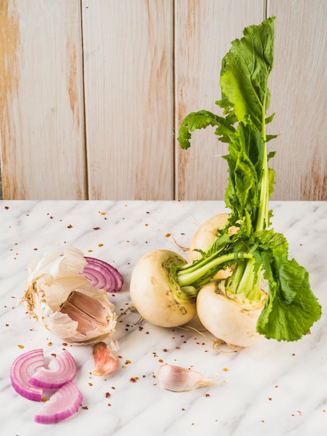 Free photo close-up of turnip; onion slice and garlic cloves on marble surface