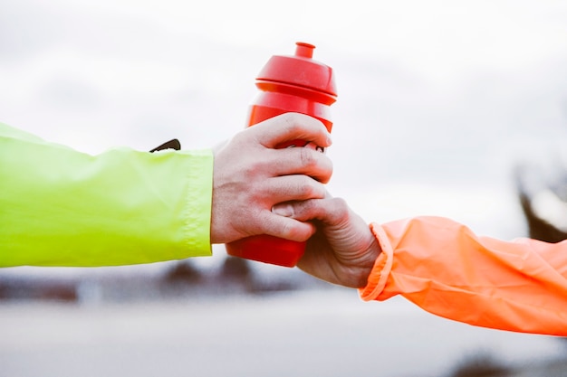 Close-up of two athlete's hand holding bottle