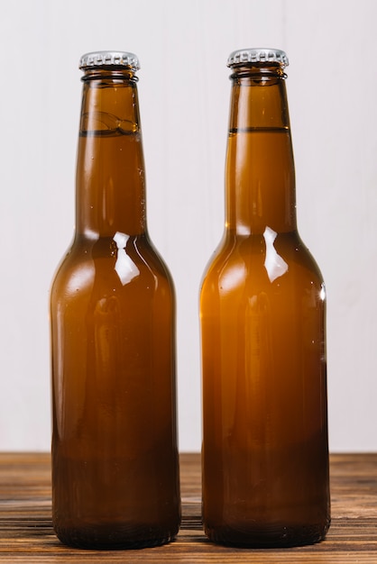 Close-up of two beer bottles on wooden table top