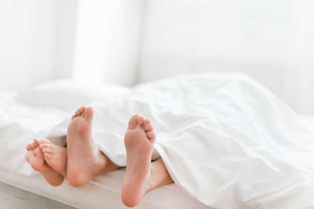 Close-up of two brother's feet on bed