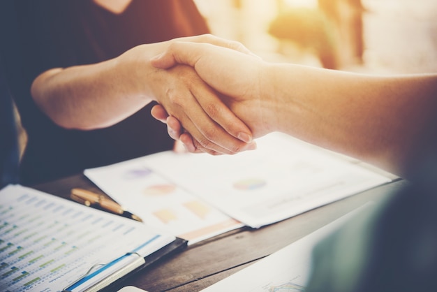 Close-up of two business people shaking hands while sitting at the working place.