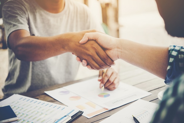 Close-up of two business people shaking hands while sitting at the working place.