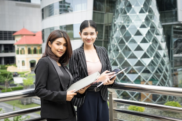 Close up of two Business woman looking with paper document together while walking to office. Business people concept.