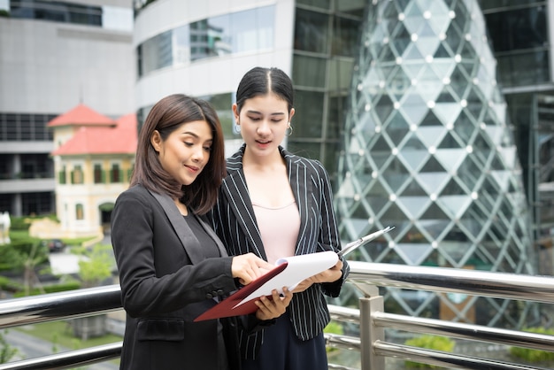Free photo close up of two business woman looking with paper document together while walking to office. business people concept.