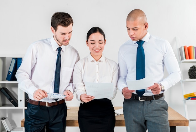 Free photo close-up of two businessman and smiling asian young businesswoman looking at financial report