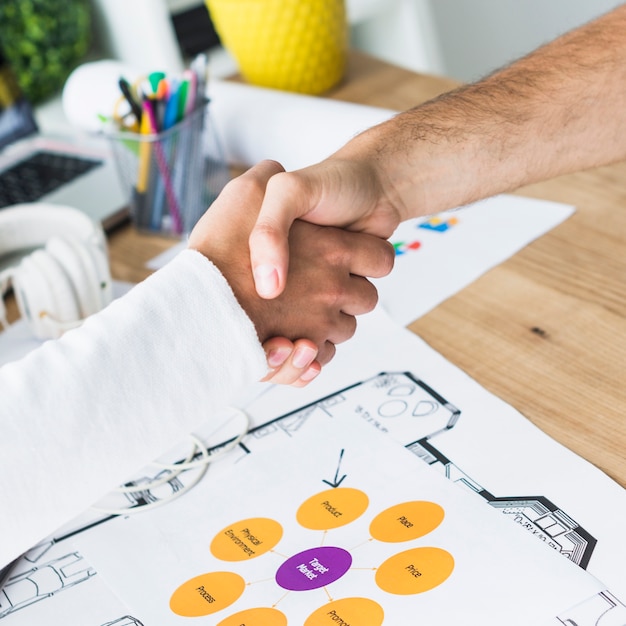 Free photo close-up of two businessmen shaking hands over desk