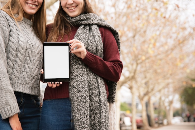 Close up two elegant women holding tablet in hands