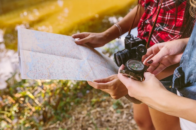 Close-up of two female friend holding compass and map