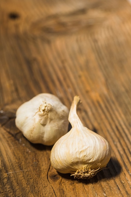 Close-up of two garlic bulbs on wooden background