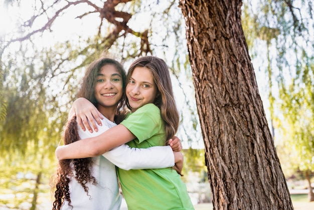 Close-up of two girls standing under the tree hugging each other