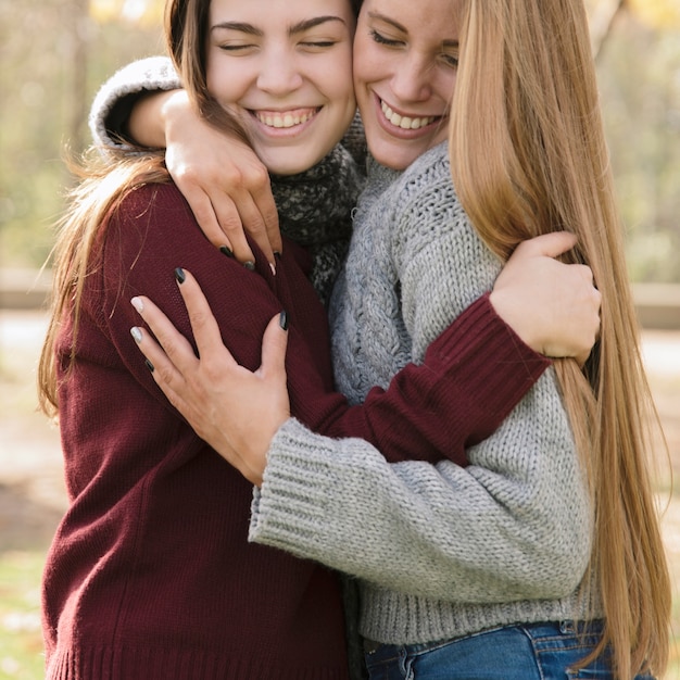 Free photo close up two hugging young women in the park