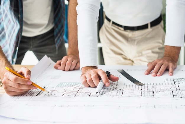 Close-up of two male architect's hand over blueprint