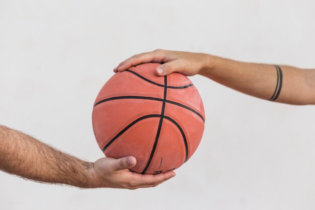 Крупный план двух мужчин, держащих баскетбол