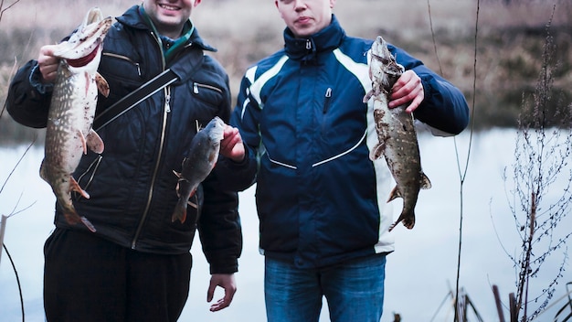 Close-up of two men holding caught fish