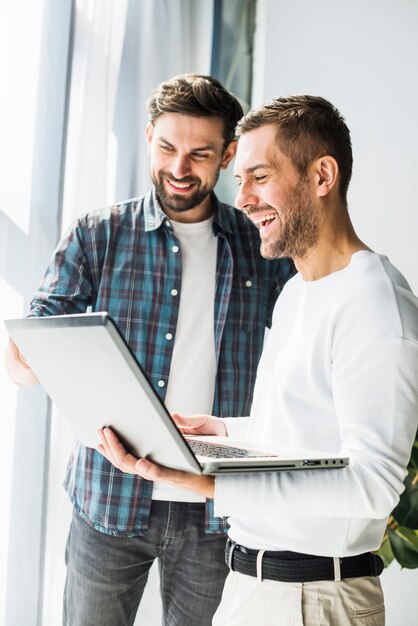 Close-up of two smiling young businessmen using laptop