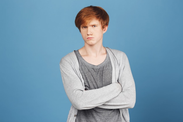 Free photo close up of unhappy young good-looking ginger boy in casual stylish outfit crossing hands,  with offended and unsatisfied face expression, after argument with girlfriend.