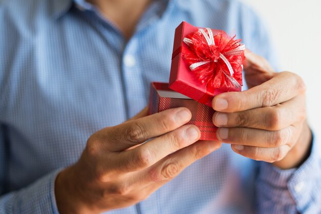 Close-up of unrecognizable man opening small red box