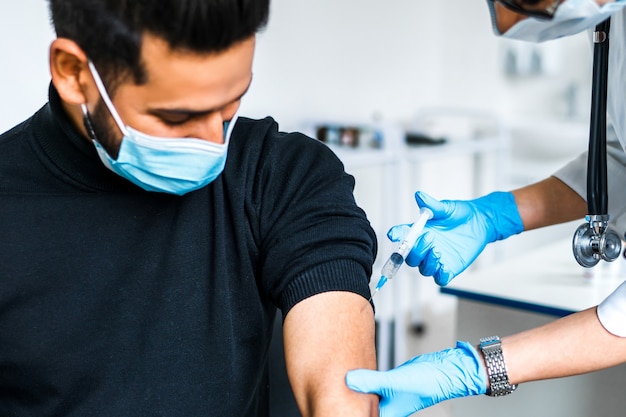 Close up of a vaccination patient, the doctor injects a coronavirus vaccine into the patient's hand.