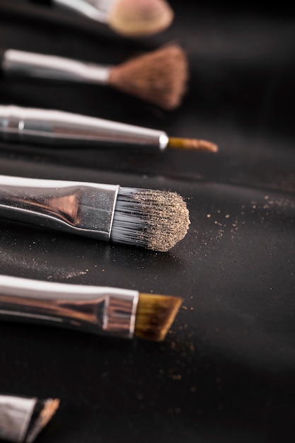 Close-up of various makeup brushes on black background