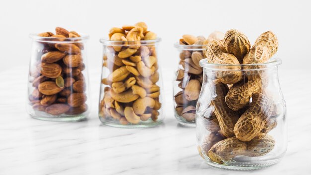 Close-up of various nut food jars on marble surface