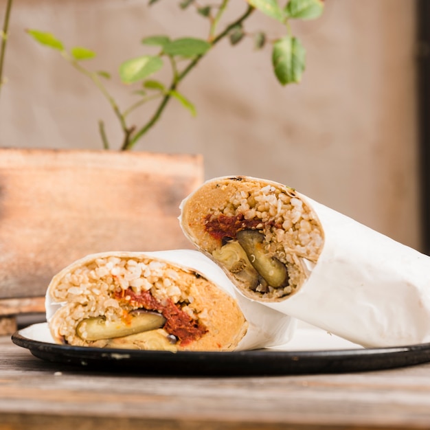 Foto gratuita close-up di involucro di burrito vegetariano sul piatto sopra il tavolo